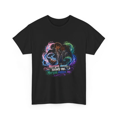 Black unisex t-shirt with fantasy art of two men, faces close as if about to kiss, framed by swirling pink, green, and blue magic, and the quote "Morgan doesn't steady me, Morgan undoes me," close-up view.