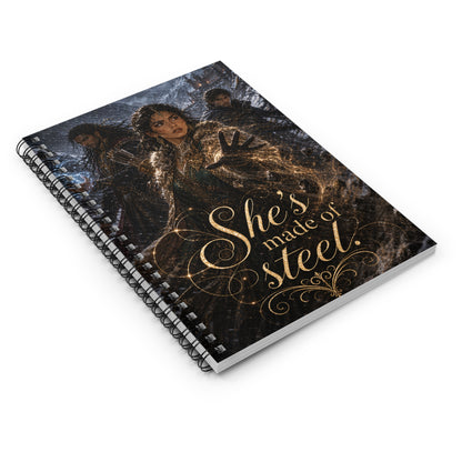 Spiral notebook lying at a three-quarter angle, cover art of a woman glowing gold between two armed men in a blizzard, quote "She's made of steel." in gold script.