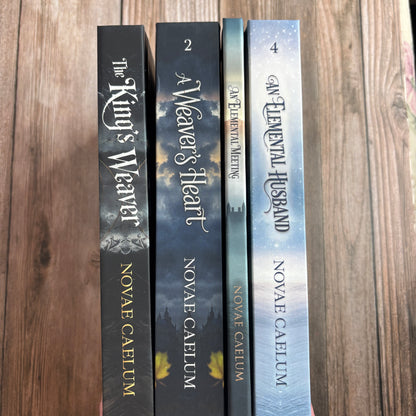 A hand holds four numbered hardcover spines from The King's Weaver series by Novae Caelum—The King's Weaver, A Weaver's Heart, An Elemental Meeting, and An Elemental Husband—against a wood background.
