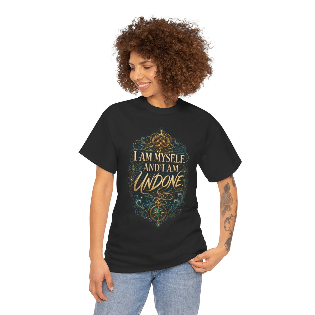 Black unisex t-shirt worn by a smiling woman with curly brown hair and a tattoo on her forearm, printed with a gold Celtic knot design and the quote "I am myself. And I am undone."