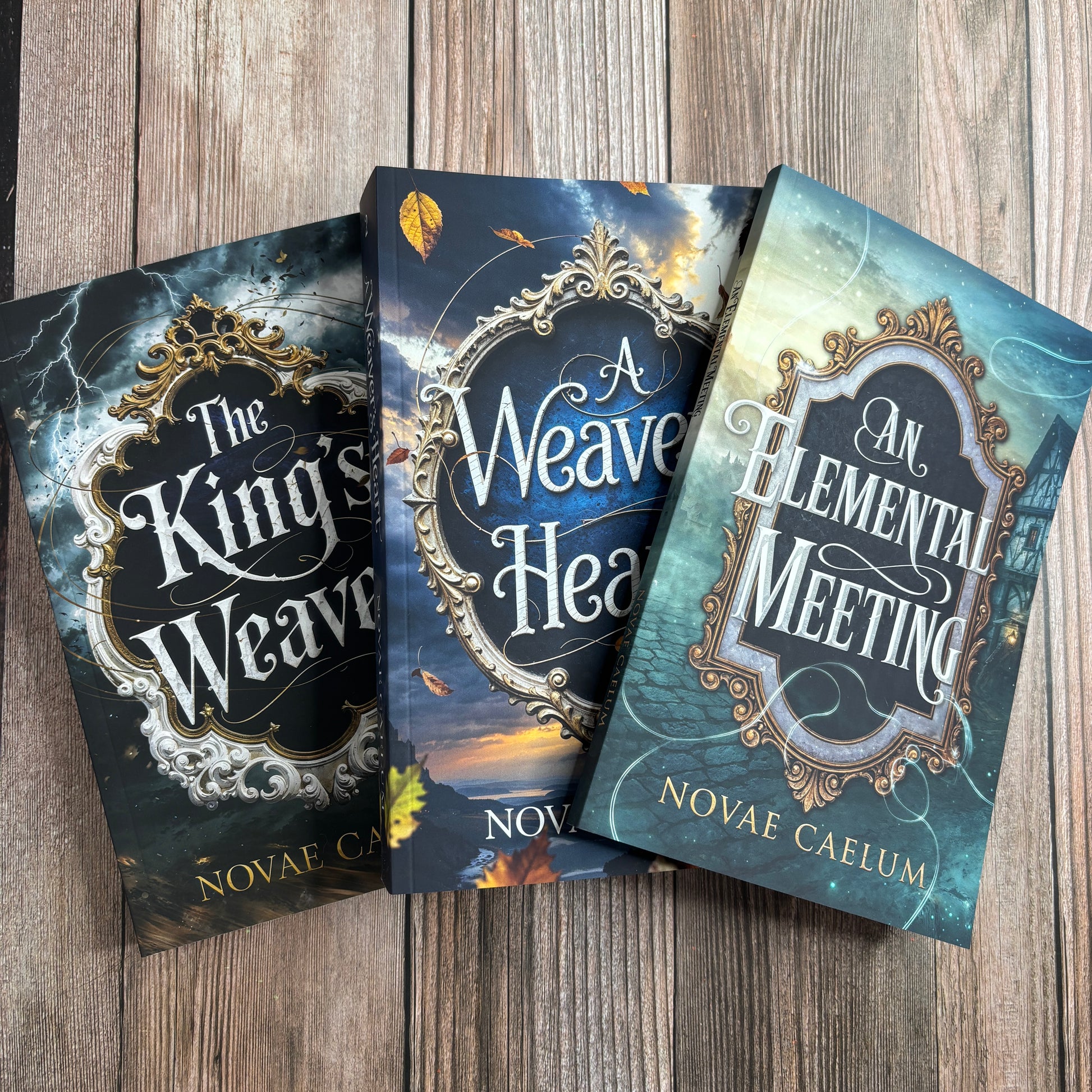 Stack of three fanned paperback books from The King's Weaver series by Novae Caelum—The King's Weaver, A Weaver's Heart, and An Elemental Meeting—on a wood-plank surface.