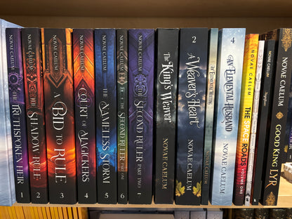 Photograph of a bookshelf holding the full paperback print run of Novae Caelum's catalog spine-out, including The Truthspoken Heir, A Bid to Rule, The King's Weaver, An Elemental Husband, The Space Roads, and Good King Lyr.