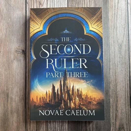 Front cover of "The Second Ruler: Part Three — The Stars and Green Magics Book 8" by Novae Caelum, paperback lying on weathered grey wood, showing an ornate blue-and-gold archway framing a golden spired city beneath a starry sky.